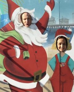 Image of two people behind a Christmas cut-out board.