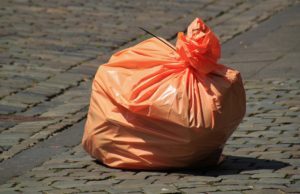image of an orange trash bag on a street as an example of simple poly packaging