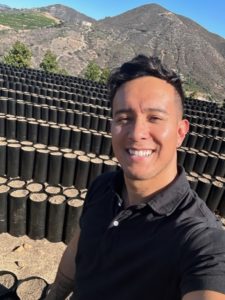 image of a sales representative from TDI Custom Packaging in front of rows of black plant bags filled with soil
