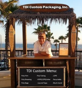 image of the owner of TDI Custom Packaging, Inc. standing behind a counter showing TDI Custom Menu choices with the beach in the background